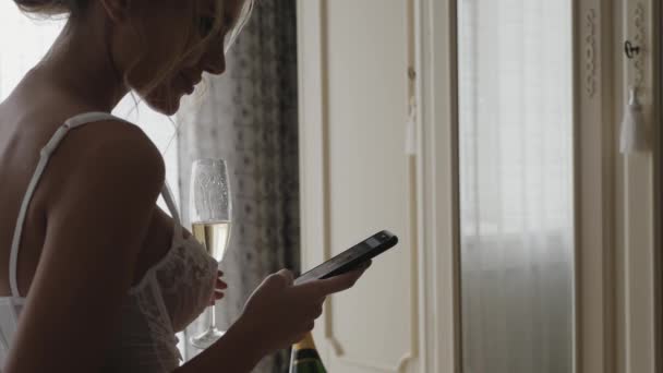 Meisje in lingerie is met behulp van een smartphone in de slaapkamer — Stockvideo