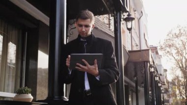 Genç adam bir takım elbise ve siyah ceket dijital tablet kullanır