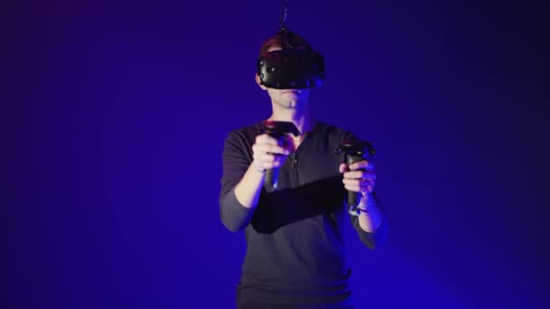 Hombre joven que usa auriculares modernos de realidad virtual con mando — Vídeo de stock