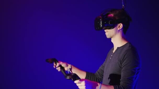 Человек использует современную гарнитуру виртуальной реальности с геймпадом — стоковое видео