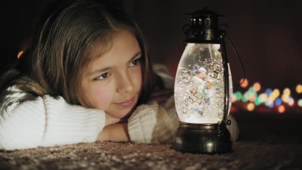 Sfera di neve di Natale e ragazza carina guardando fiocchi di neve e luci — Video Stock