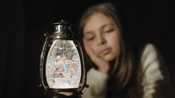 Christmas snow globe and cute girl watching snowflakes and lights — Stock Video