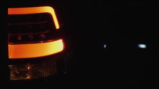 Luz trasera del automóvil parpadea en el fondo oscuro — Vídeo de stock