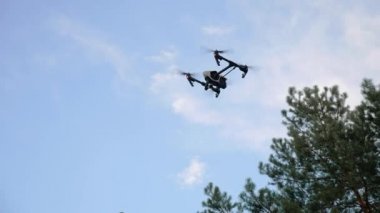 Alt görünümü. Mavi bir gökyüzü bulutlu bir ağaç yakınındaki hava quadrocopter dron dondu. Kamera, hava anket işaret