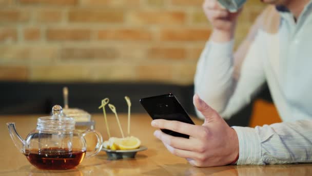 Joven usa smartphone mientras desayuna en una cafetería — Vídeo de stock