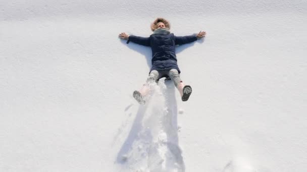 Vue du dessus d'une fille faisant un ange de neige — Video
