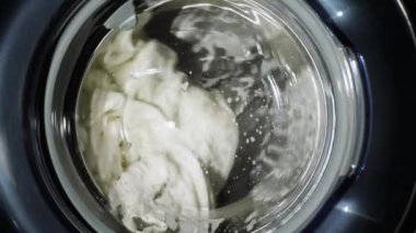 Çamaşır makinesi beyaz giysiler yıkar. Yakın çekim yavaş vurdu. Silindir iplik. Kimse