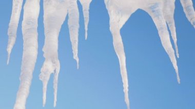 Bahar tezcan, buz buz sarkıtları mavi gökyüzü arka plan, yakın çekim vurdu. Kamera yavaş yavaş yukarıdan aşağıya doğru taşır..