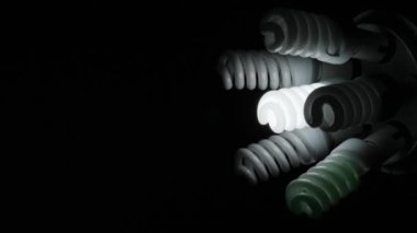 Altı eko-enerji tasarrufu spiral ampul açmak birbiri ardına karanlık bir arka plan üzerinde. Lambalar açmak