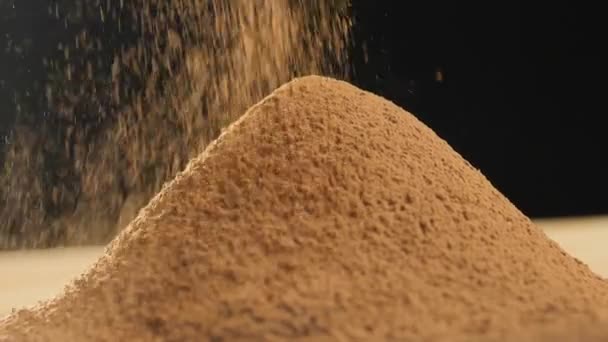Primer plano del tamizado del tamiz de cacao en polvo sobre un fondo oscuro — Vídeos de Stock
