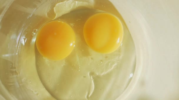 L'œuf tombe dans un bol en verre sur la table au ralenti 