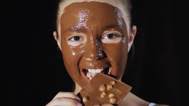 Νεαρό κορίτσι δαγκώνει μια μπάρα σοκολάτας — Αρχείο Βίντεο