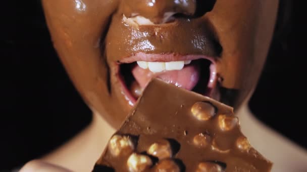 Gros plan d'une fille qui mord une barre de chocolat . — Video