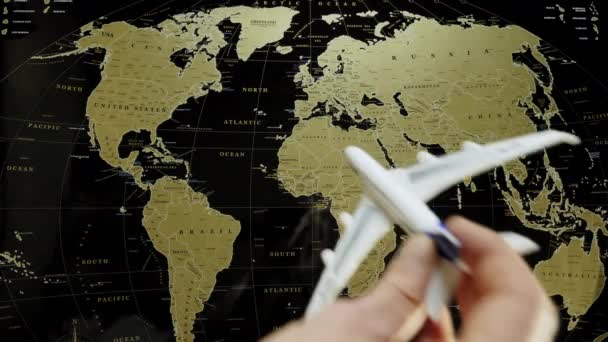 A toy passenger plane in a human hand lands on a world map — Stock Video