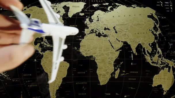 Um avião de passageiros de brinquedo em uma mão humana pousa em um mapa do mundo — Vídeo de Stock