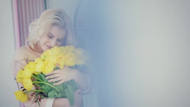 A menina gosta do aroma de um buquê de tulipas amarelas — Vídeo de Stock