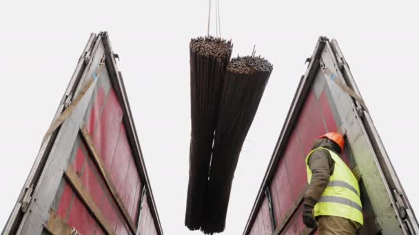 Les travailleurs utilisant une grue déchargent un faisceau de tiges d'acier — Video