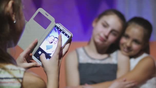 Девушка-подросток с помощью мобильного телефона и фотографирует своих подружек — стоковое видео