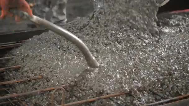 Close-up shot van beton gieten op versterking van metalen staven van een plaat — Stockvideo