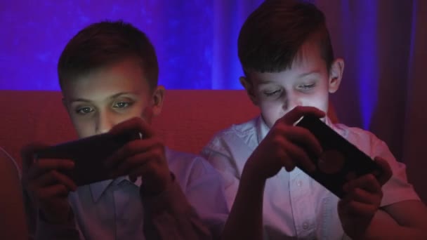 Dois meninos bonitos jogando videogame com telefone inteligente na sala — Vídeo de Stock