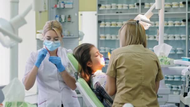 Ortodoncista brilla en los dientes con una lámpara de fotopolímero — Vídeo de stock