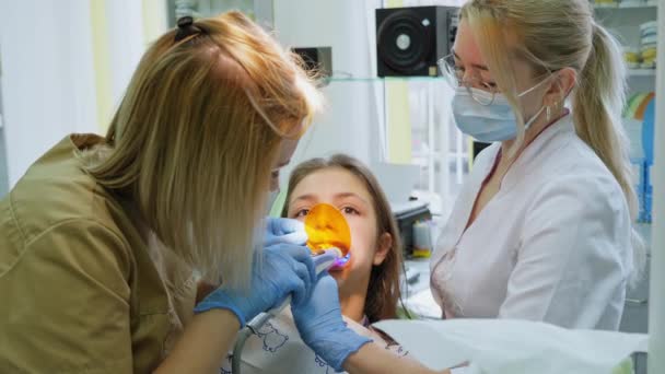 Ортодонт світить на зубах фотополімерною лампою — стокове відео