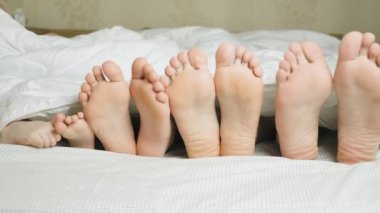 Aile ayaklar içinde yatak altında beyaz battaniye