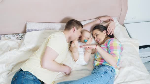 Любящие родители со своим милым маленьким сыном на кровати — стоковое видео