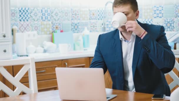 Adam dizüstü bilgisayarda çalışıyor ve kahve içiyor. — Stok video
