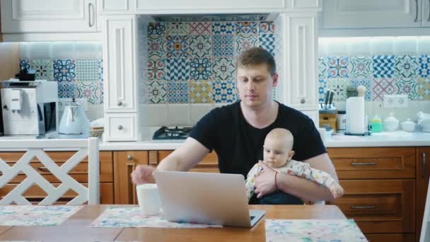 Single μπαμπάς που εργάζεται σε ένα φορητό υπολογιστή με το μωρό — Αρχείο Βίντεο