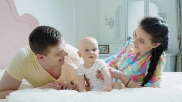 Happy family - mother, father and baby on the bed in the morning — Stock Video