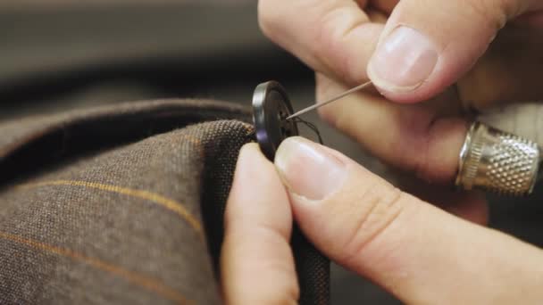 Nähen eines Knopfes auf eine braune Jacke maßgeschneiderten Anzug — Stockvideo
