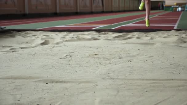 Lány sportoló teljesítő hosszú ugorj be homokozóban — Stock videók