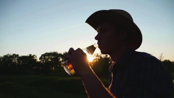 Silhouette dell'uomo che beve birra durante il tramonto — Video Stock