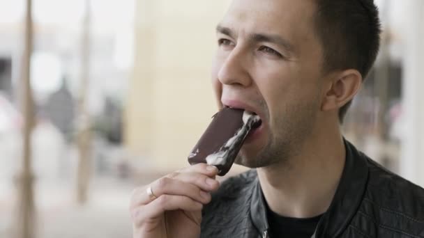 Joven guapo comiendo un helado de chocolate — Vídeos de Stock