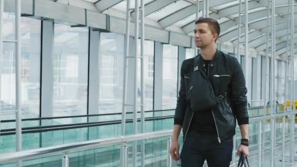 Um jovem homem confiante com uma bolsa no moderno terminal aeroportuário — Vídeo de Stock