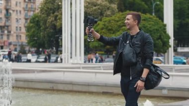Genç bir erkek blogcu bir şehir caddesinden video blogu yayınlıyor