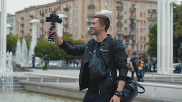 Jovem blogueiro masculino transmitindo vídeo blog de uma rua da cidade — Vídeo de Stock