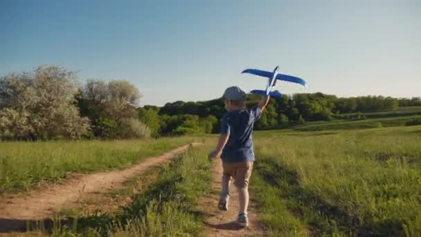 Un niño corre con un avión de juguete en la mano — Vídeos de Stock