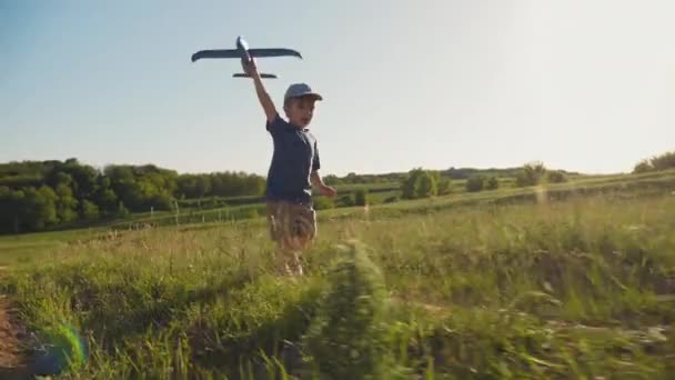 Un niño corre con un avión de juguete en la mano — Vídeo de stock