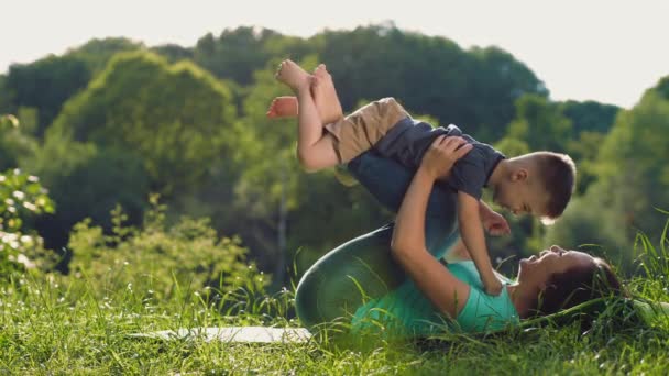 Küçük oğlu ile anne jimnastik egzersiz açık havada yapıyor — Stok video