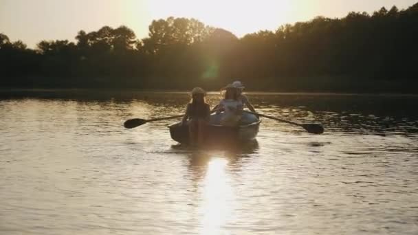 Сім'я плаває в човні з веслами на заході сонця — стокове відео