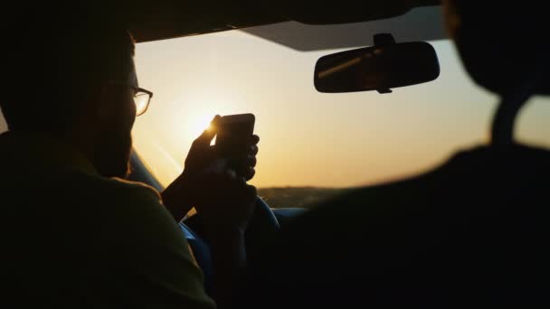 Hombre barbudo usando teléfono inteligente mientras está sentado en el coche — Vídeo de stock
