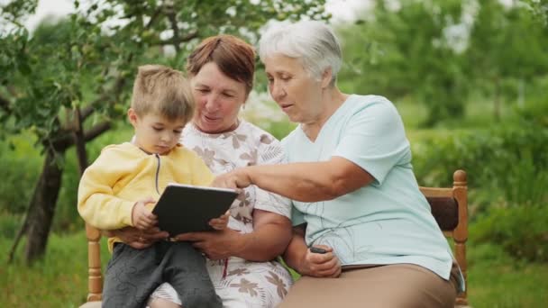 Deux grands-mères et petit-fils jouant à des jeux sur la tablette — Video