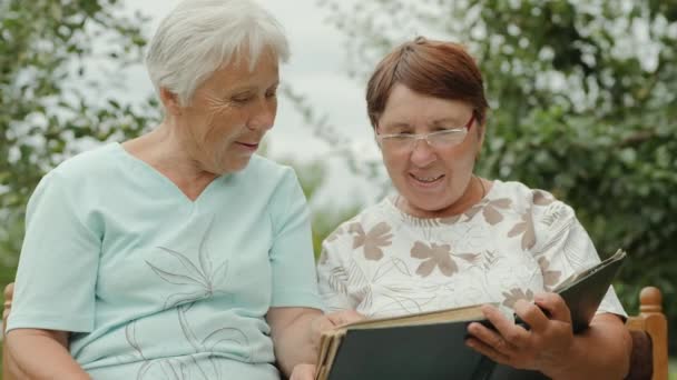 Twee oudere vrouwen bekijken Foto's buitenshuis — Stockvideo