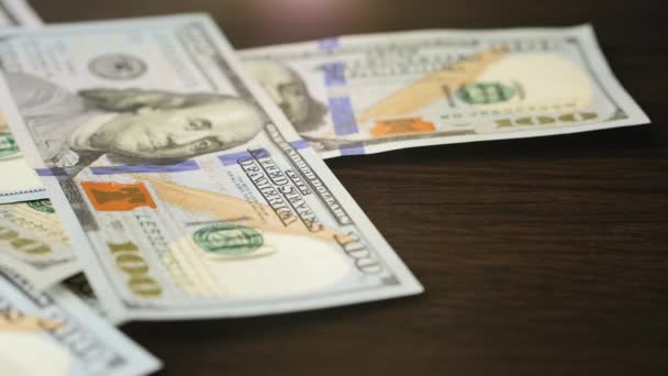Banconote da cento dollari che cadono su un tavolo di legno marrone — Video Stock