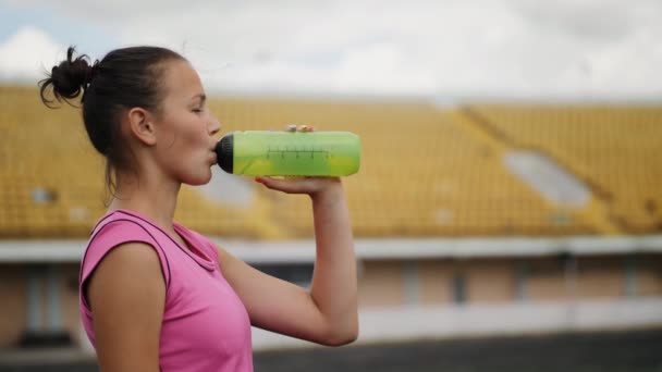 Dívka pije vodu na stadionu — Stock video