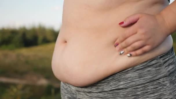 Den överviktiga flickan skakar hennes feta mage, närbild — Stockvideo