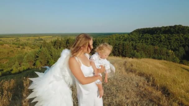 Dziewczyna z dzieckiem w ramionach jest ubrana jak anioły — Wideo stockowe