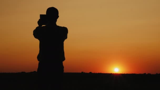 Silueta muže, který fotografuje západ slunce — Stock video